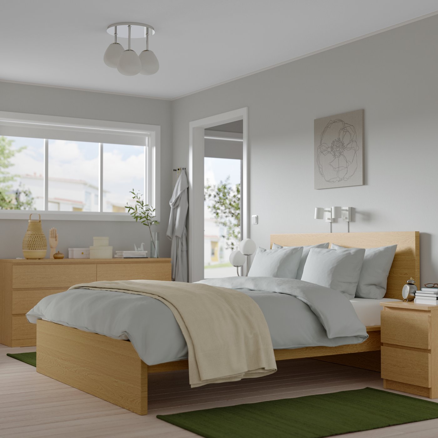 Bright bedroom with light wood furniture, gray bedding and a large window letting in natural light.