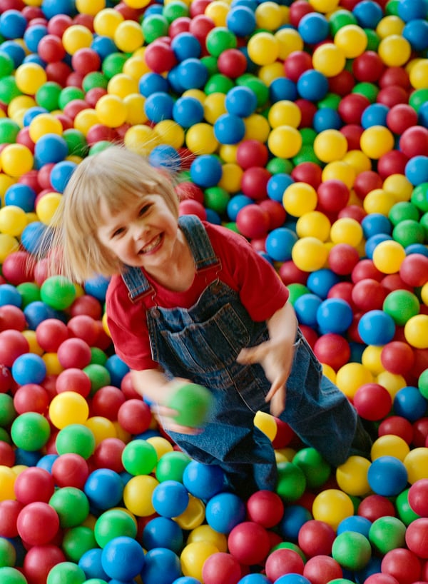 Una bambina che sorride in una piscina di palline piena di palline colorate.
