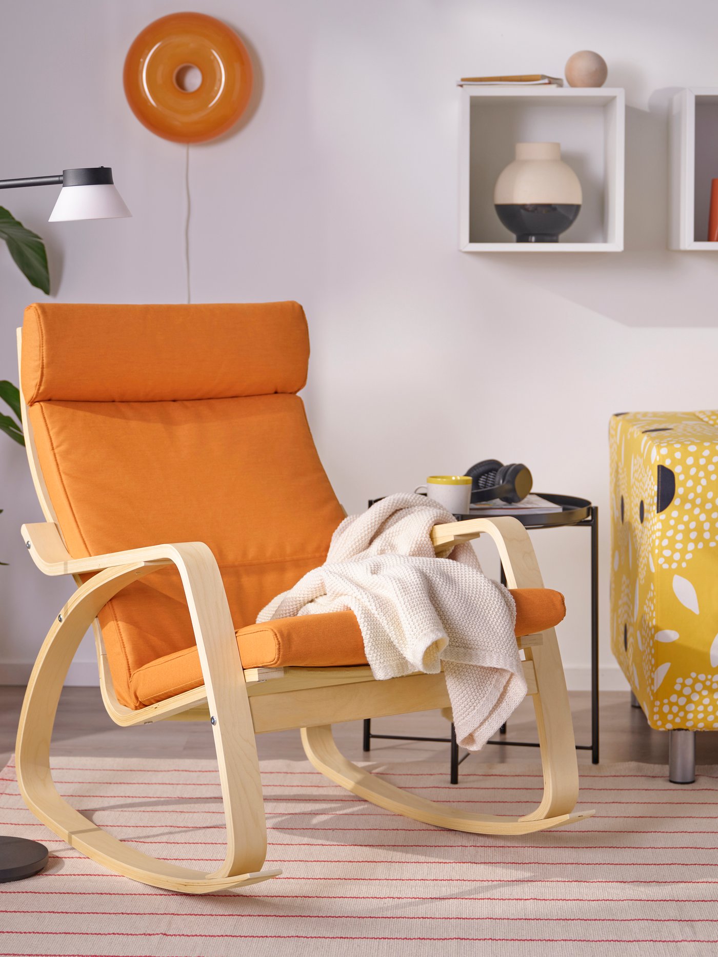 Ein POÄNG Schaukelstuhl aus Birkenfurnier mit Knisa Bezug in leuchtendem Orange.