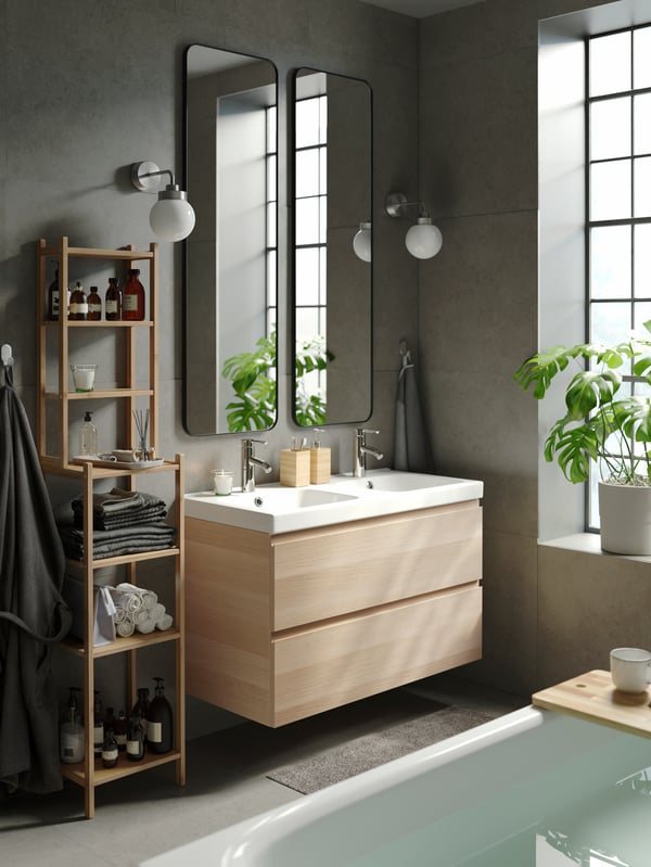 A contemporary, bright bathroom with grey walls, two LINDBYN mirrors above a wash-stand with double wash-basins and drawers.