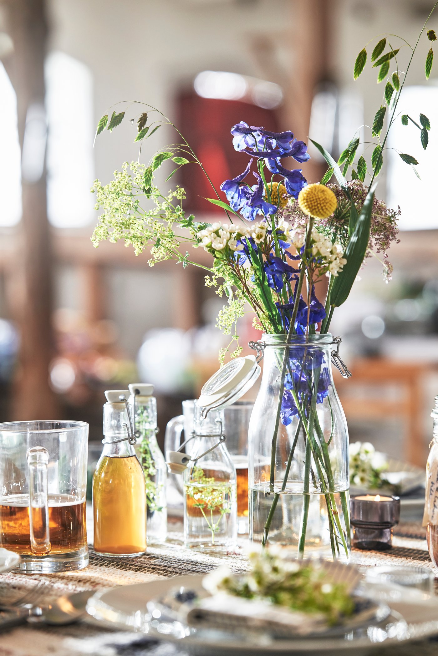 En vacker bukett med färggranna sommarblommor i en glasvas fungerar som mittpunkt på ett festligt dukat middagsbord.