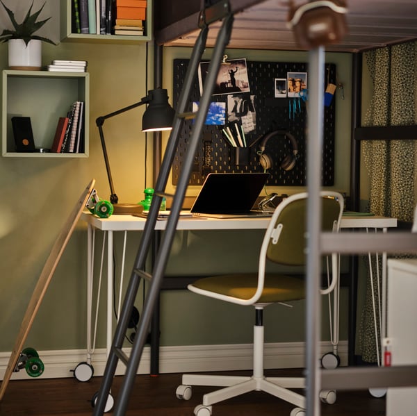 Geelgroene ÖRFJÄLL bureaustoel bij een bureau met laptop, onder een donkergrijze TUFFING hoogslaper.