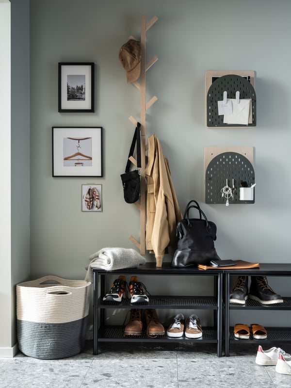A hallway with garments on TJUSIG vertical hook racks, notes on VATTENKAR wall storage units, and shoes on PINNIG benches.