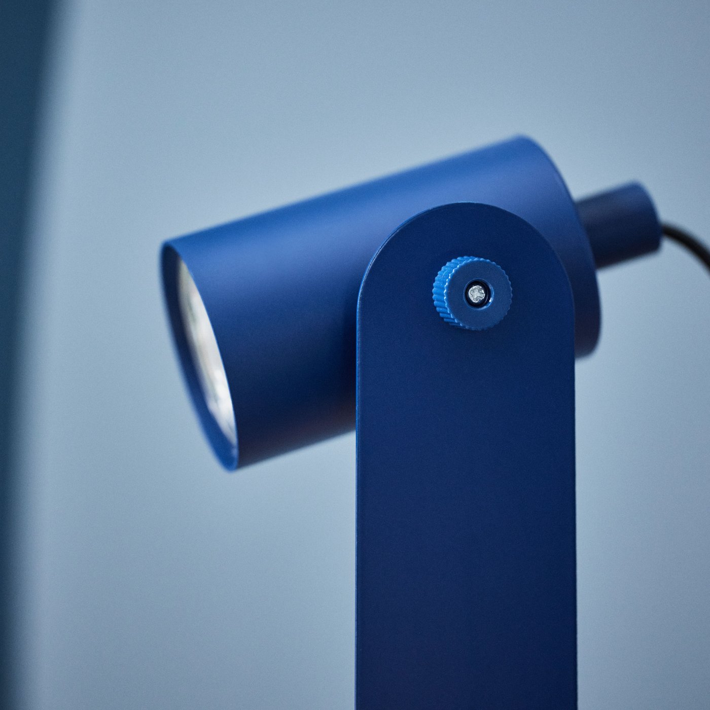 A blue Ikea lamp in profile that is directed diagonally downwards.