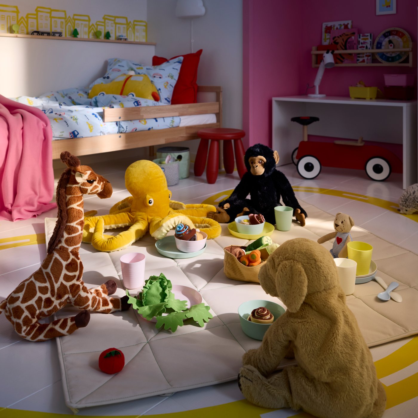 En lekhörna i ett barnrum där mjukdjuret BLÅVINGAD är placerat bland andra gosedjur som har picknick.
