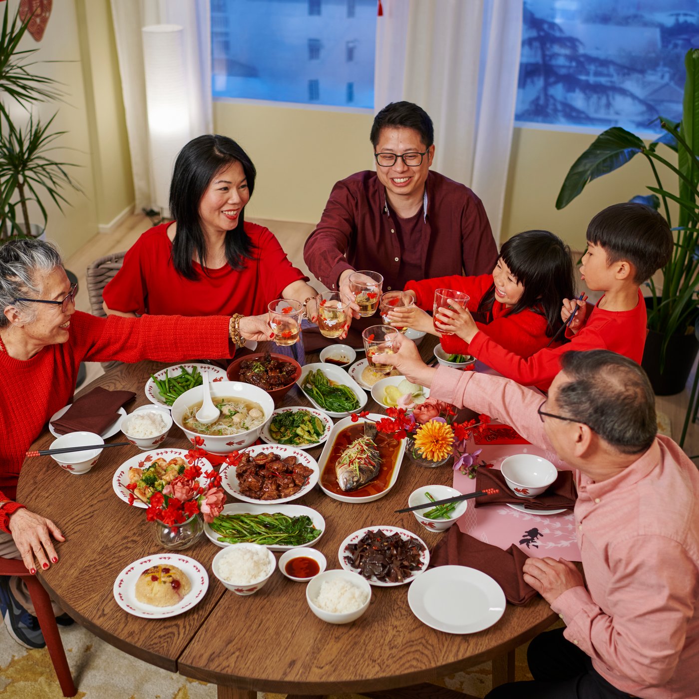 Asian family dressed in red eating reunion dinner at a round SKANSNAS extendable dining table during Chinese New Year