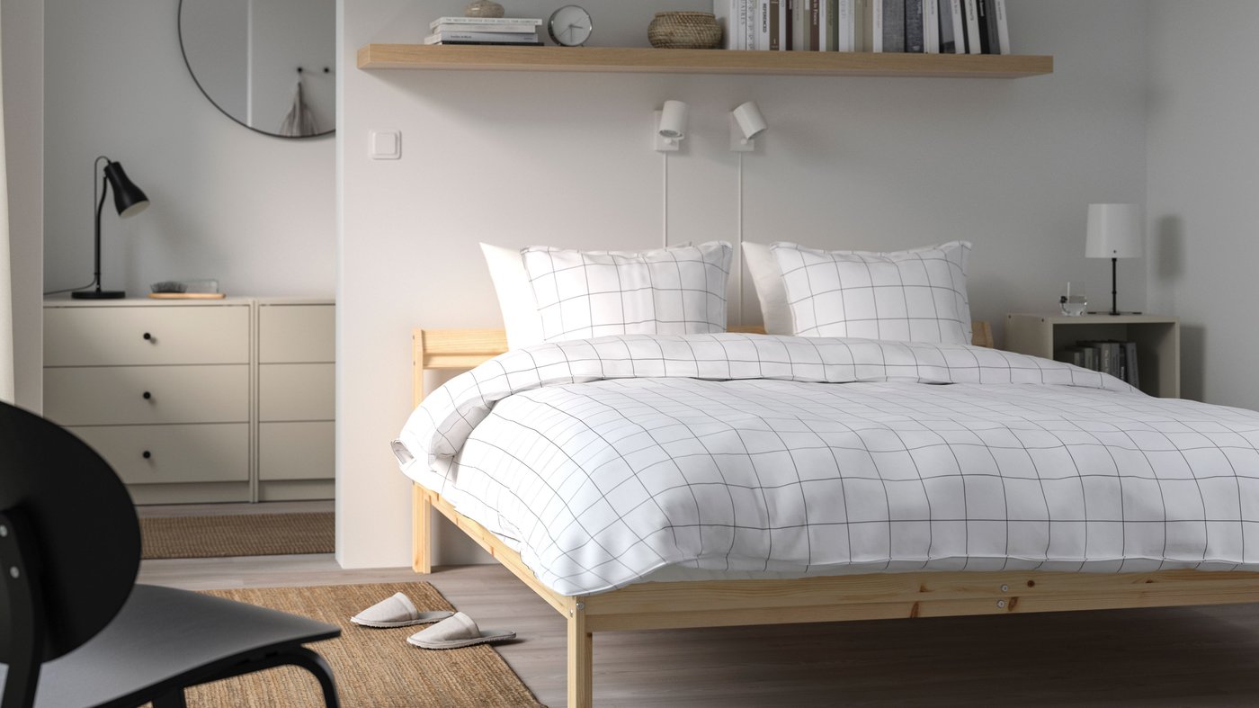 Una base de cama NEIDEN de pino en una recámara.