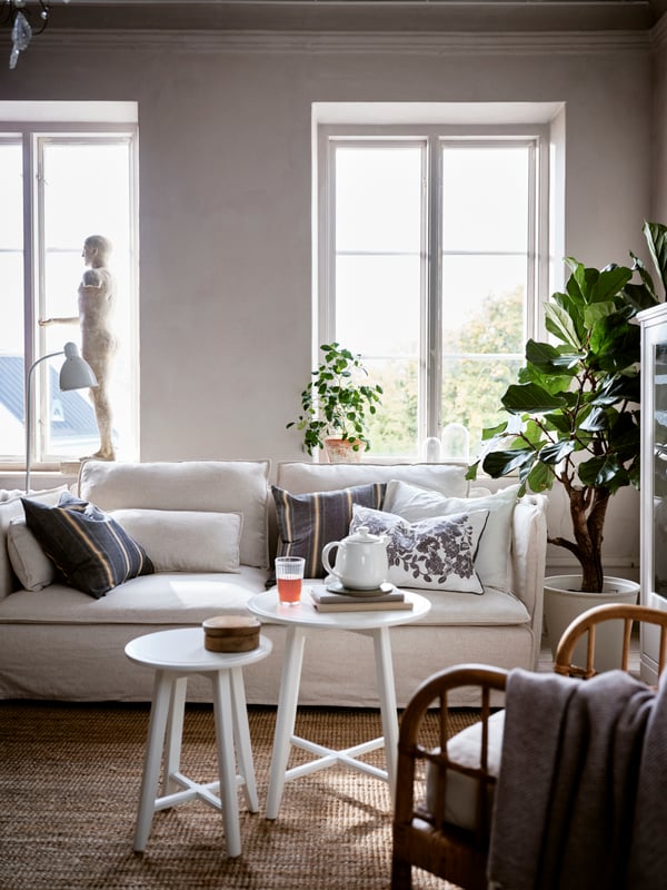 SÖDERHAMN sofa u dnevnoj sobi, na kojoj su raznobojni jastučići, uključujući SKUGGNÄVA jastučić s cvetnom šarom.