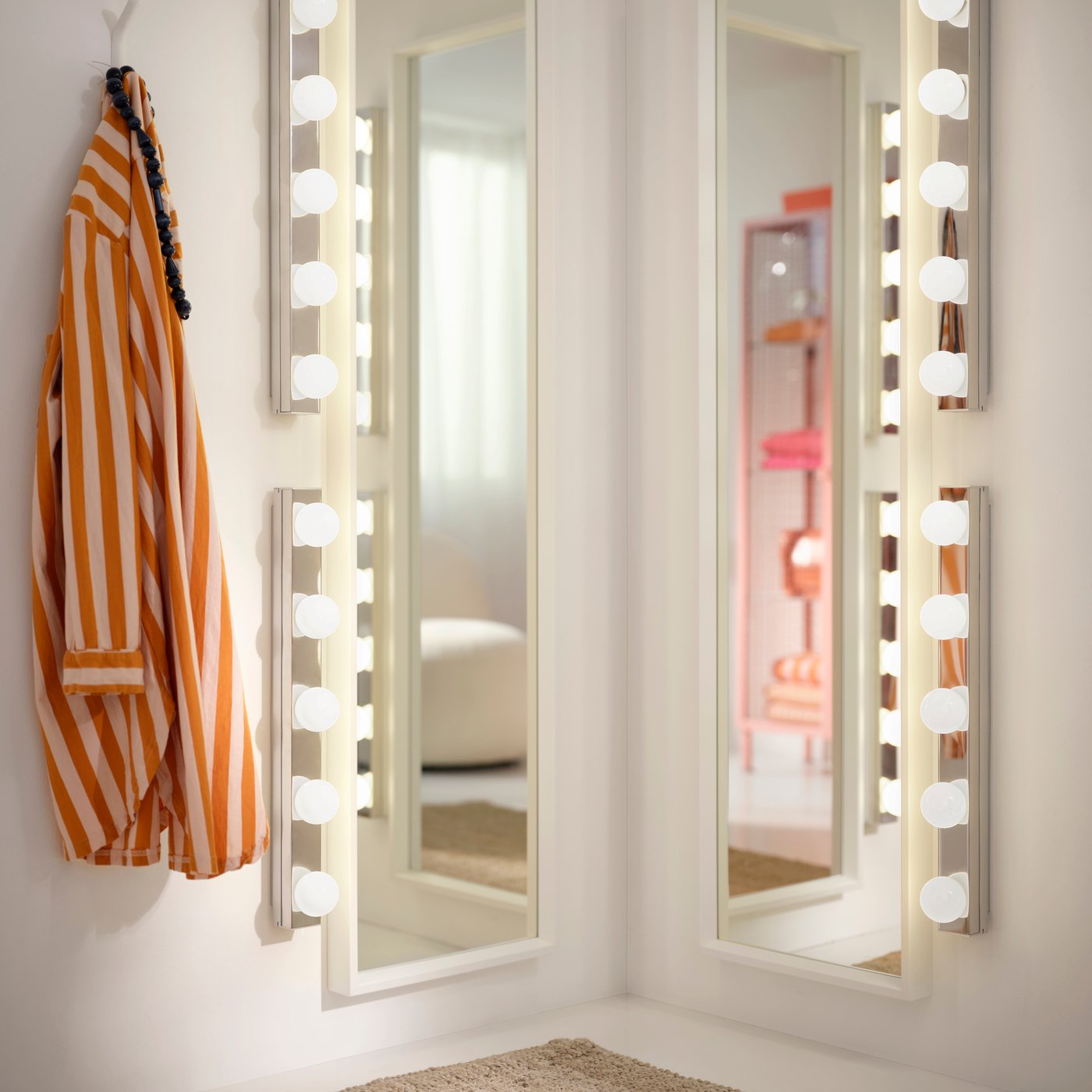 Two NISSEDAL mirrors mounted in a corner, surrounded by lamps and a striped shirt on a hook.