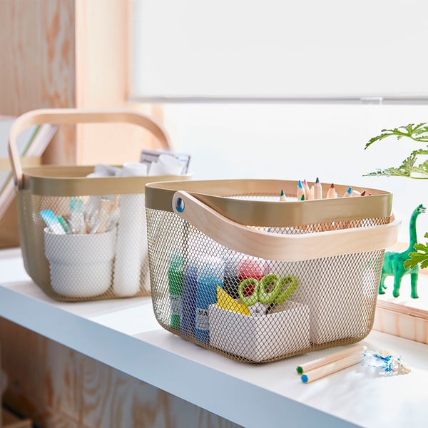 Deux paniers de rangement remplis de fournitures de bureau sont posés sur une table blanche.