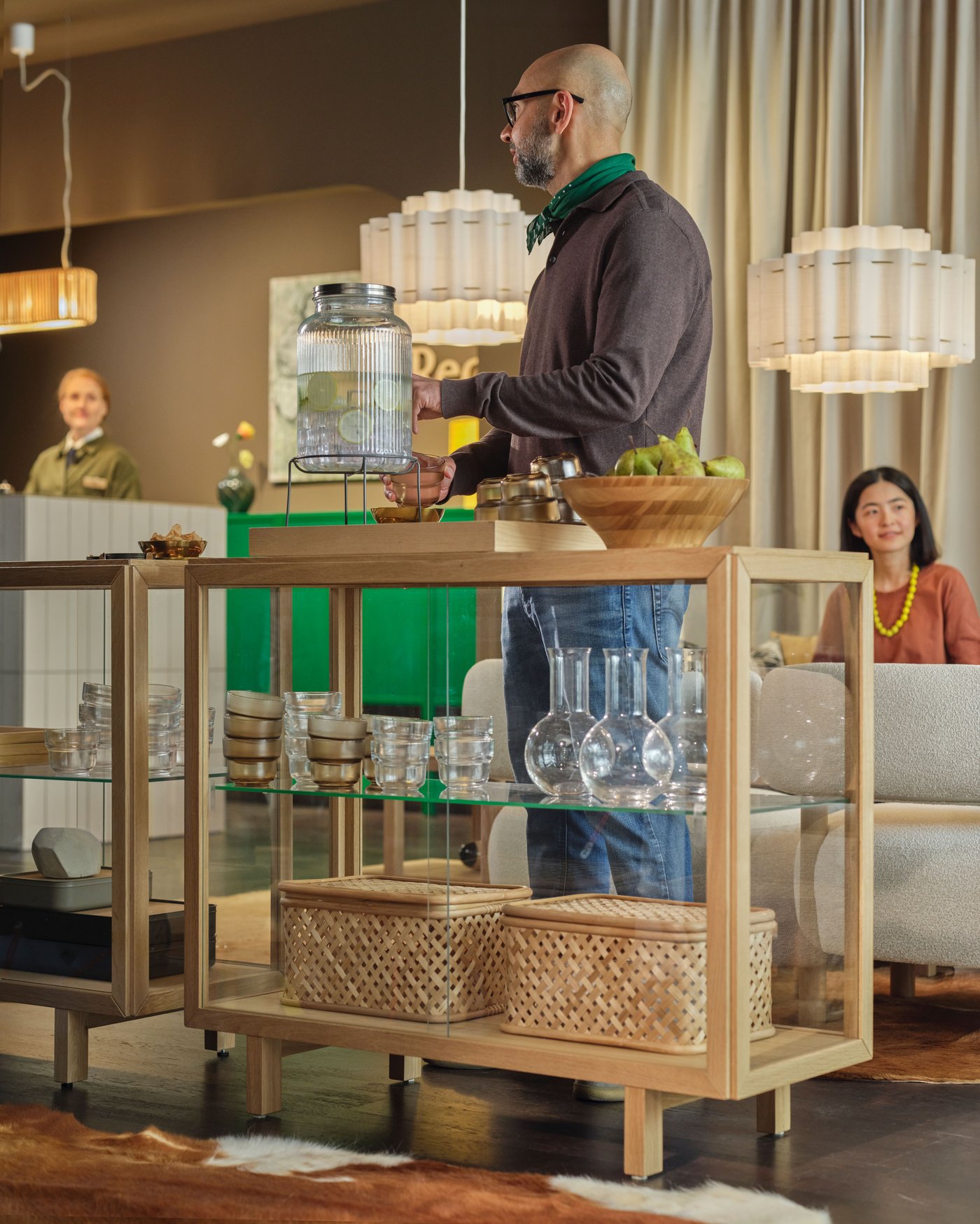 A person is standing at a drink station in a hotel lobby and is getting themselves a drink from a drink dispenser.