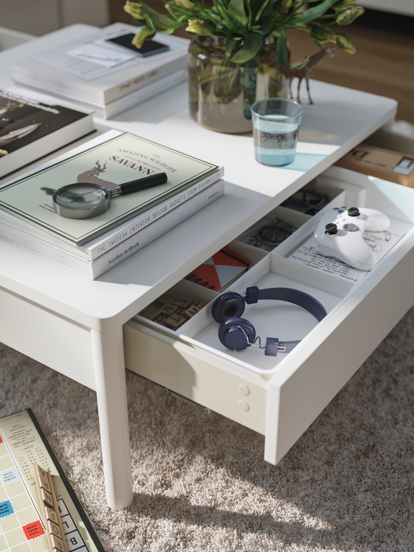 A low TONSTAD coffee table with vanity books on top and an open drawer displaying gaming gear and other equipment.