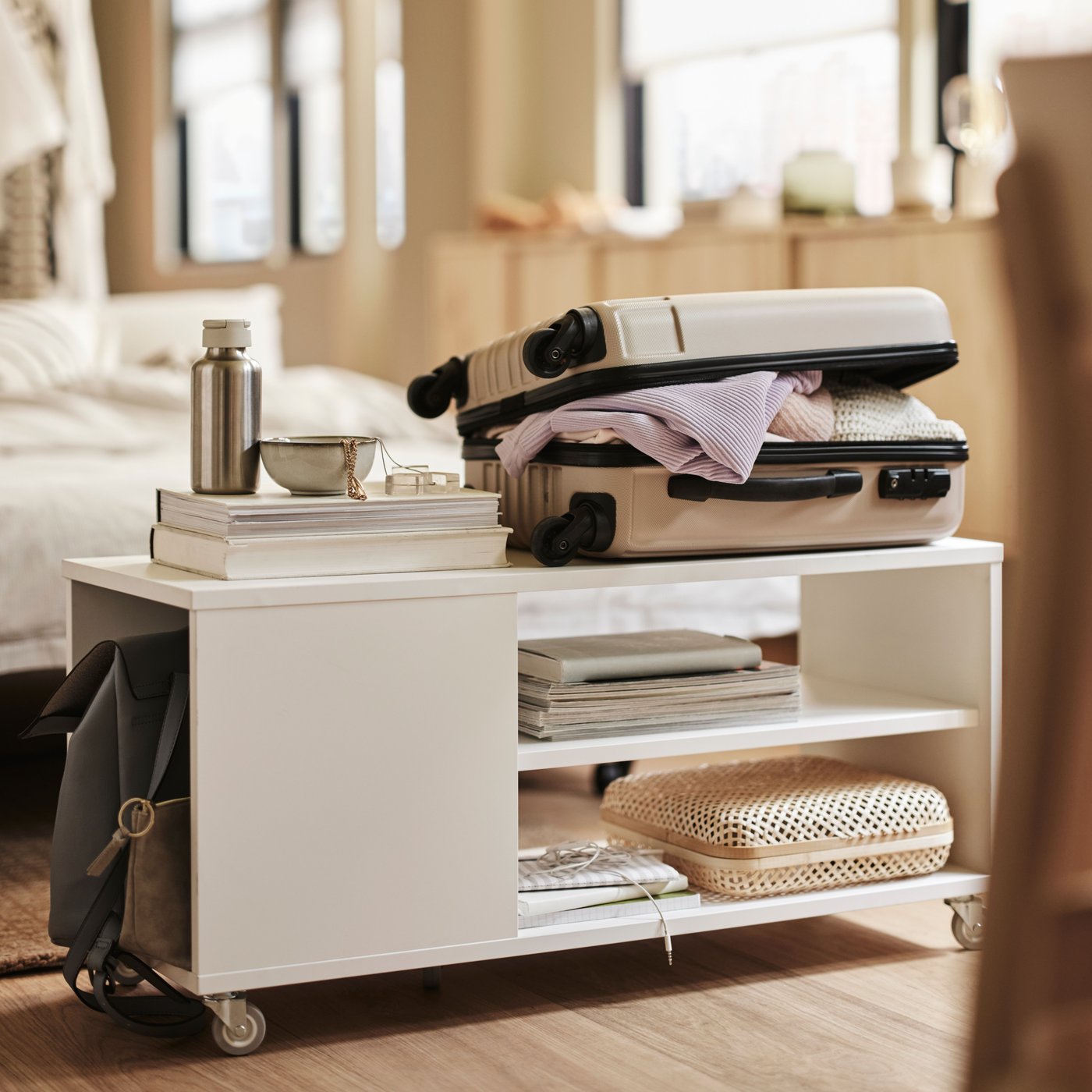 VIHALS coffee table on wheels in the middle of a room, with a suitcase on top and books and boxes on the shelves.