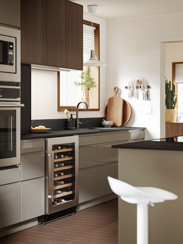 A straight kitchen with a window has base cabinets in VOXTORP high-gloss dark grey-brown and wall cabinets in SINARP brown.