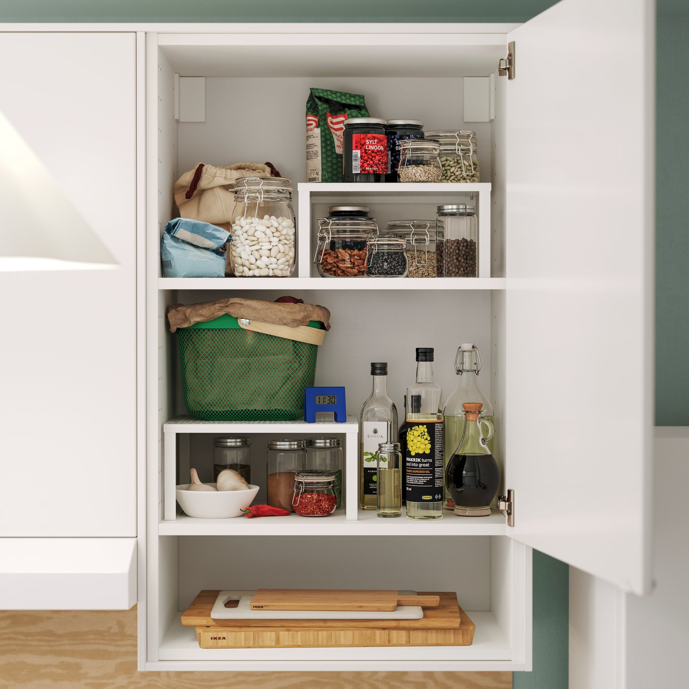 A white VARIERA shelf insert holds jars and bottles, neatly organised in a modern kitchen cabinet with food items.
