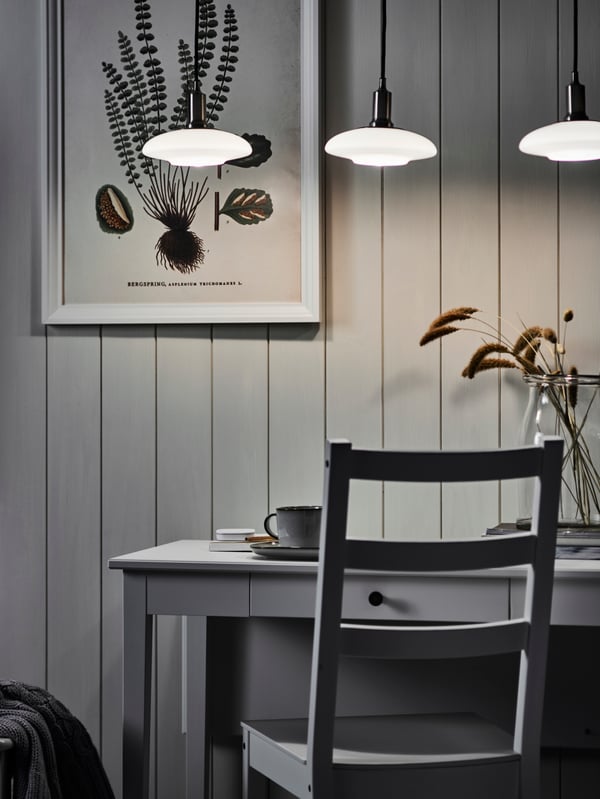 A chair stands at an IDANÄS drop-leaf table. A TÄLLBYN pendant lamp with 3 lamps hangs over the table.