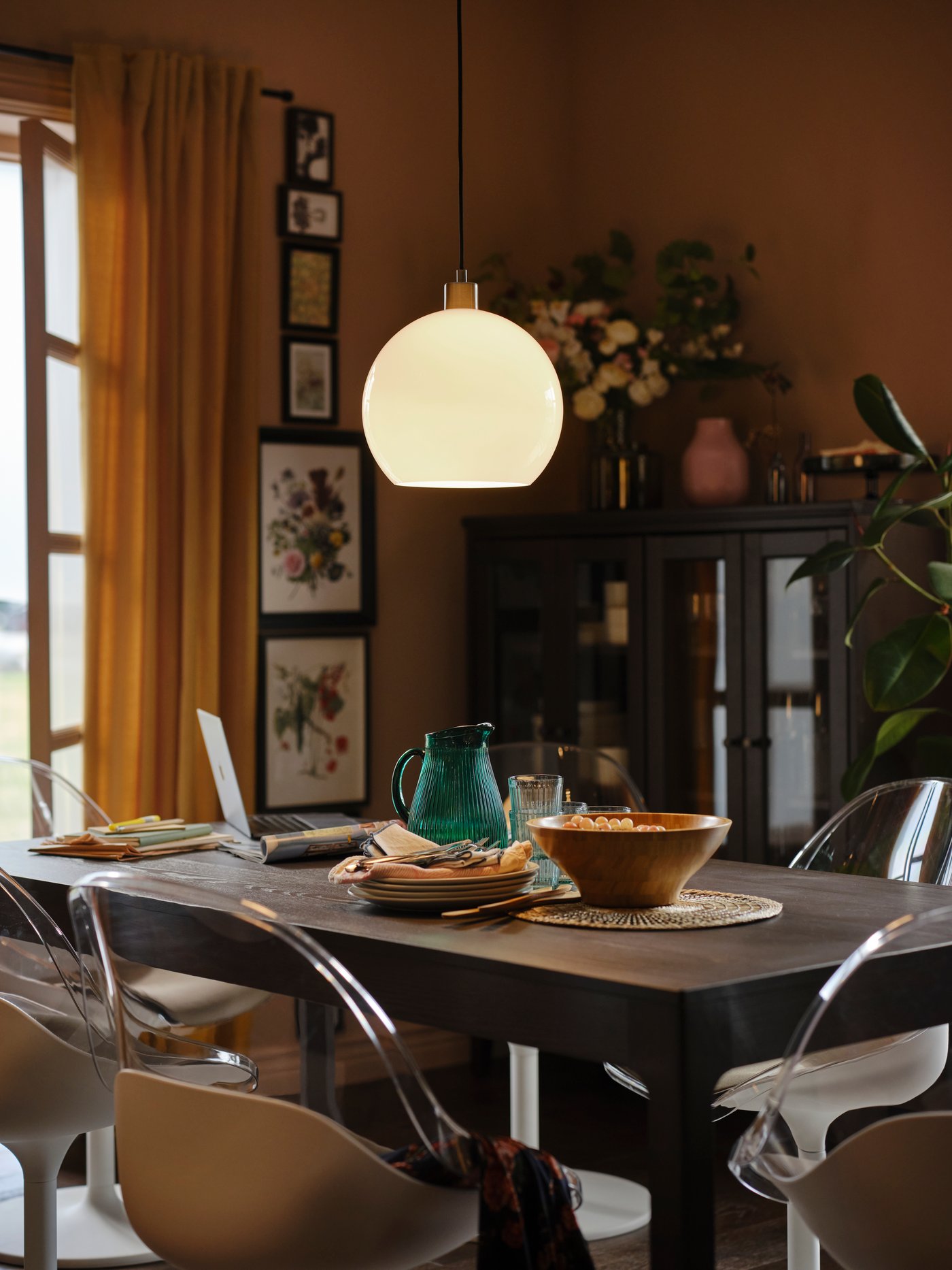 Un comedor con mesas transparentes tiene una lámpara colgante encendida.