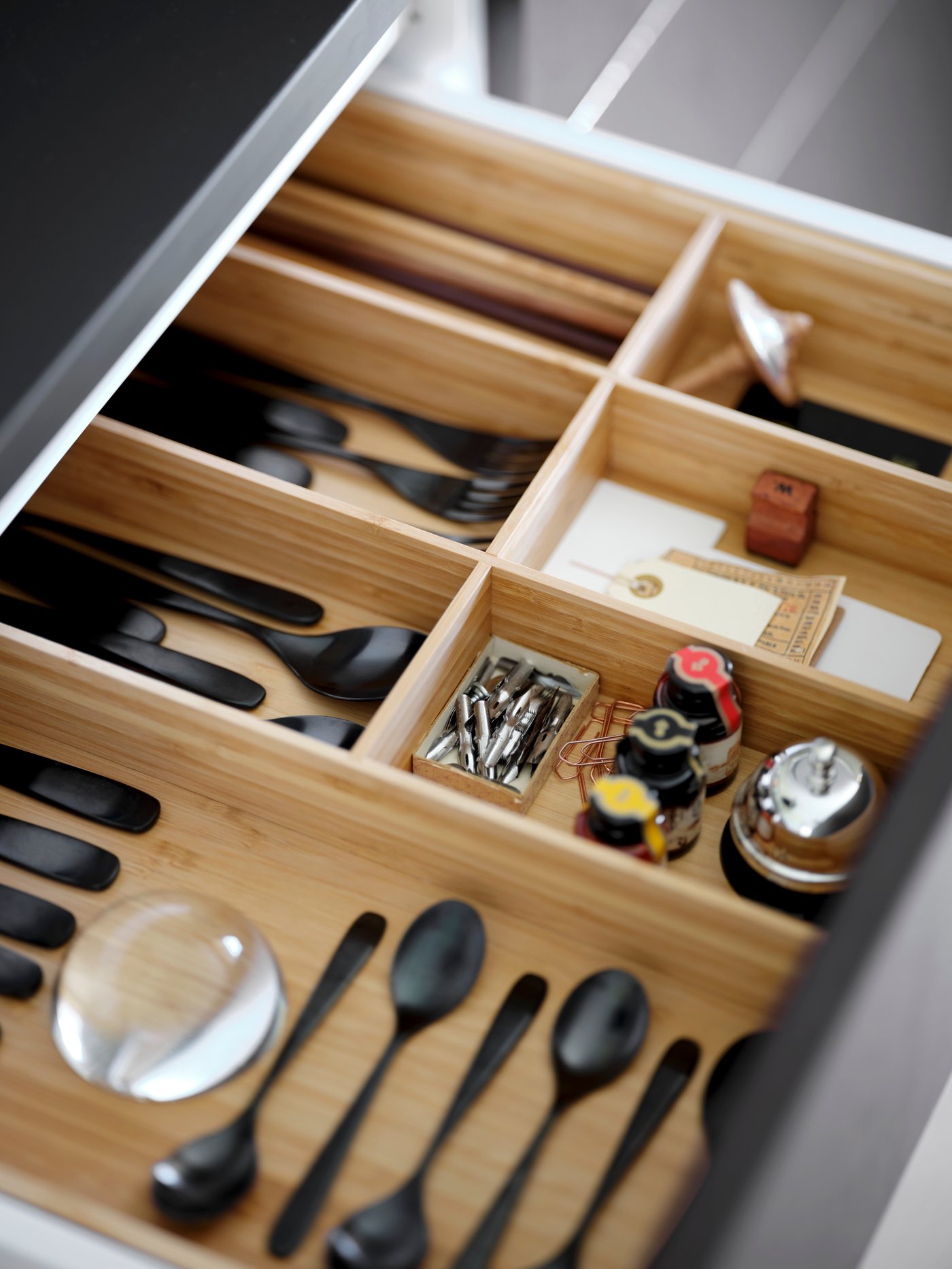 An open drawer with VARIERA organisers filled with black cutlery.