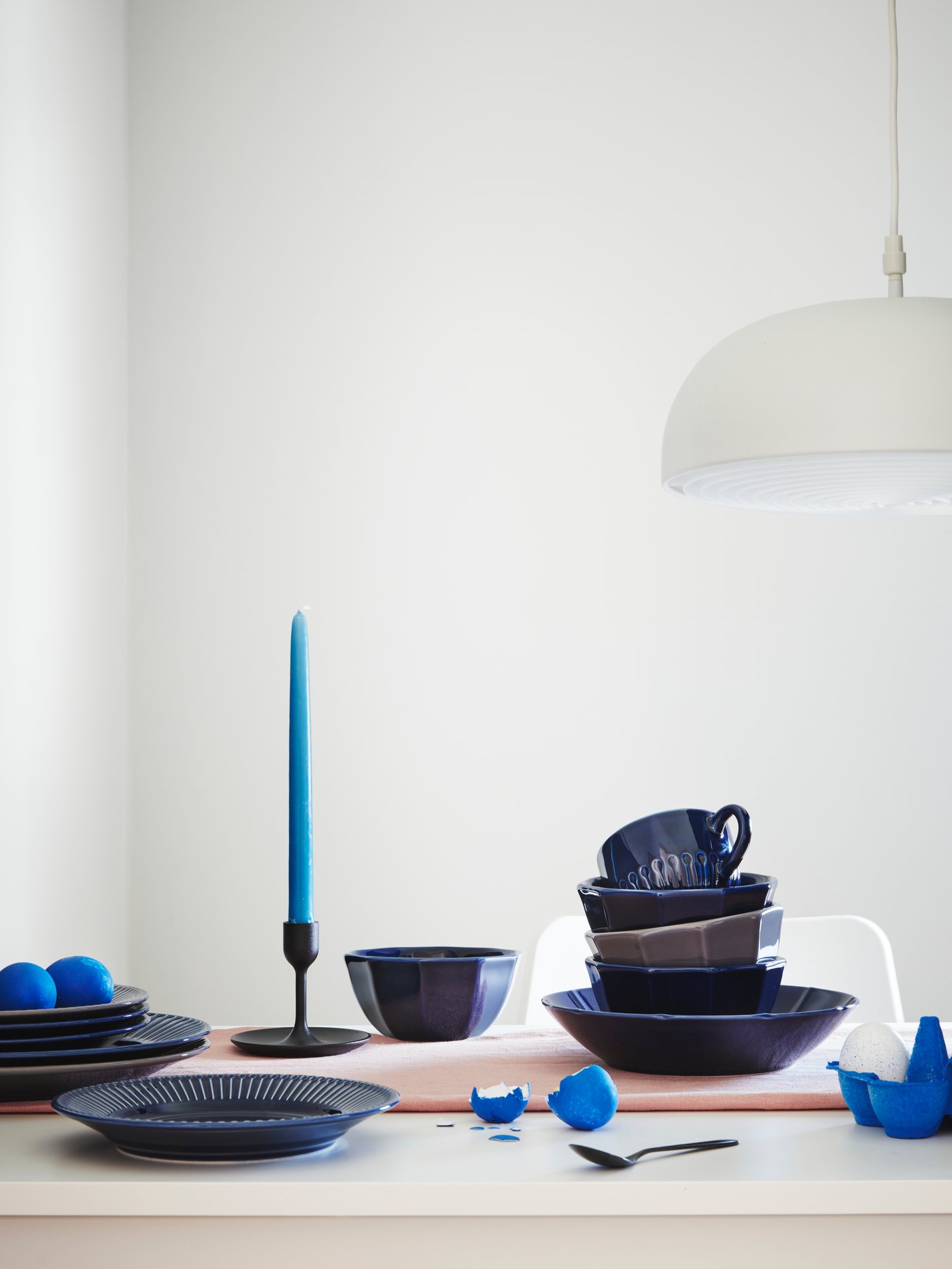 A table setting with STRIMMIG flower-inspired tableware in green. There is also a white plate with two eggs on the table.