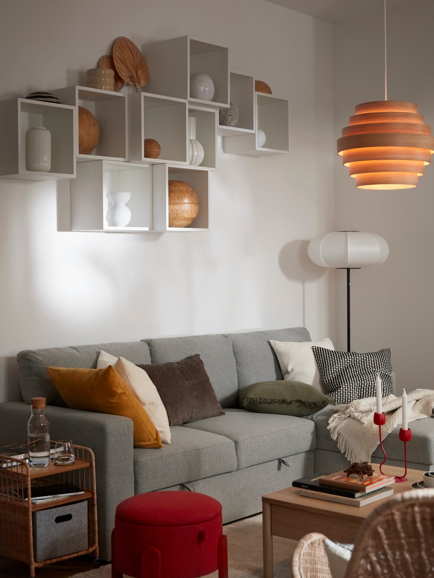 A grey FRYKSÅS armchair with cushions, with EKET cube cabinets mounted on the wall in the living room.