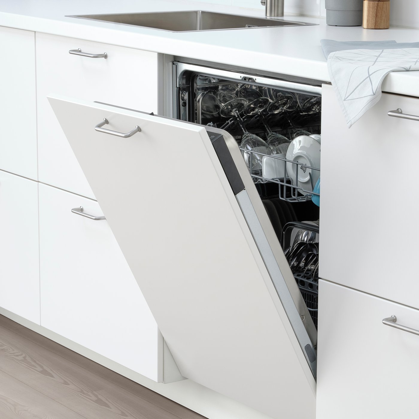 Ein IKEA Einbaugeschirrspüler in einer weissen Küche. Hinter der geöffneten Tür ist sauberes Geschirr zu erkennen.