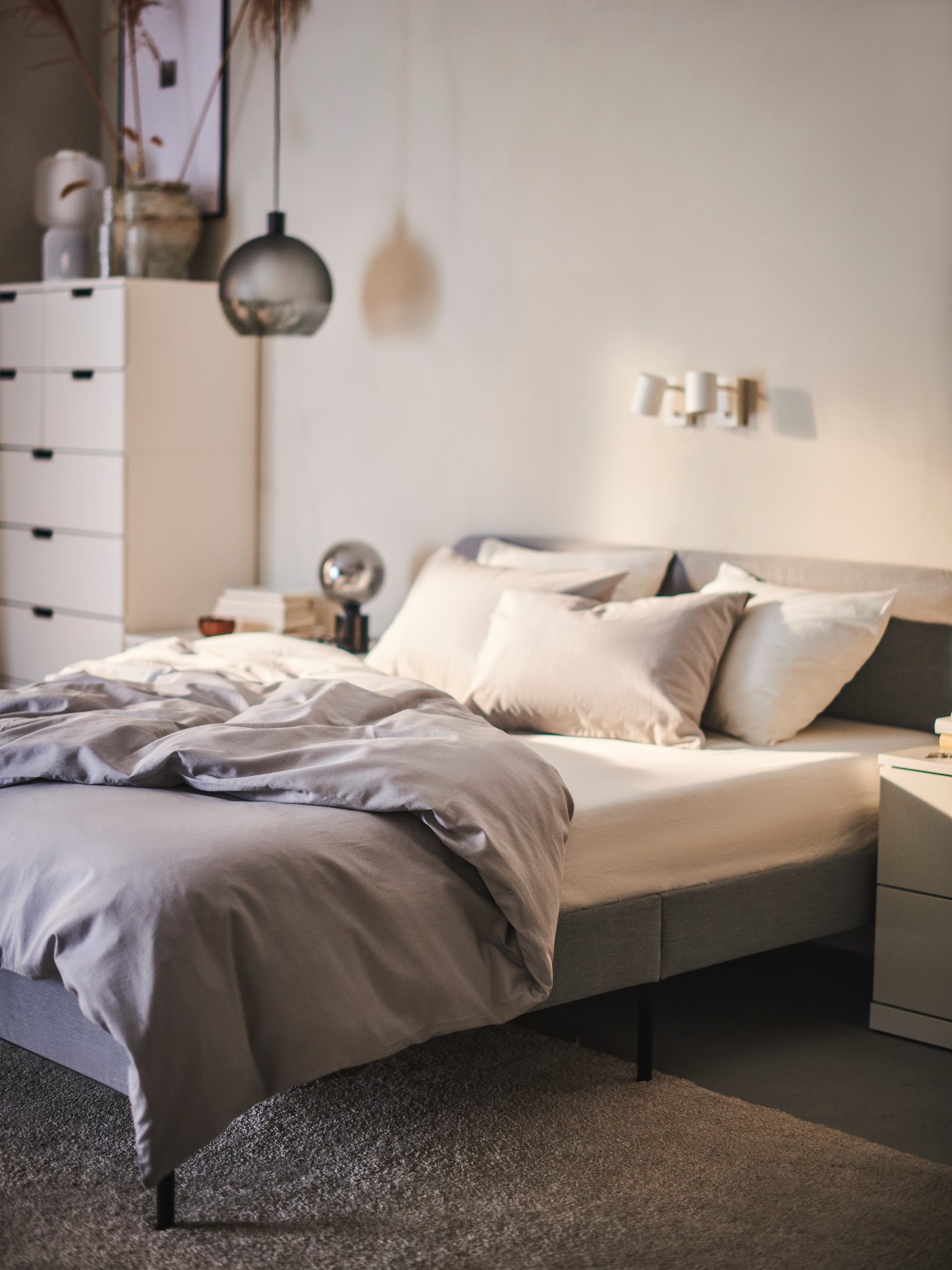 Cama tapizada con una funda de plumón NATTSVÄRMARE color gris.