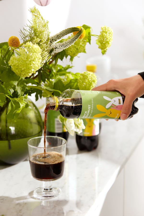 A hand pouring some DRYCK PÅSKMUST Swedish Easter drink into a glass.