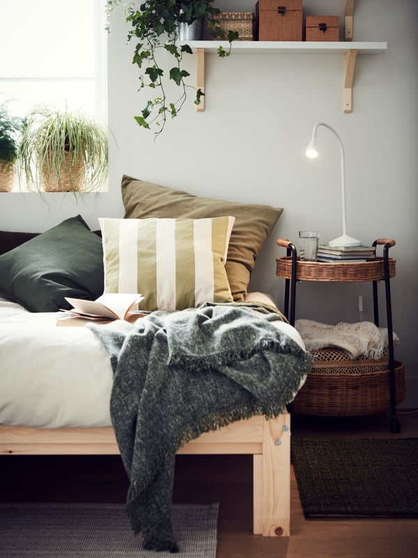 Cushions in different cushion covers, including a HILDAMARIA cushion cover, on a NEIDEN bed covered in white bed linen.