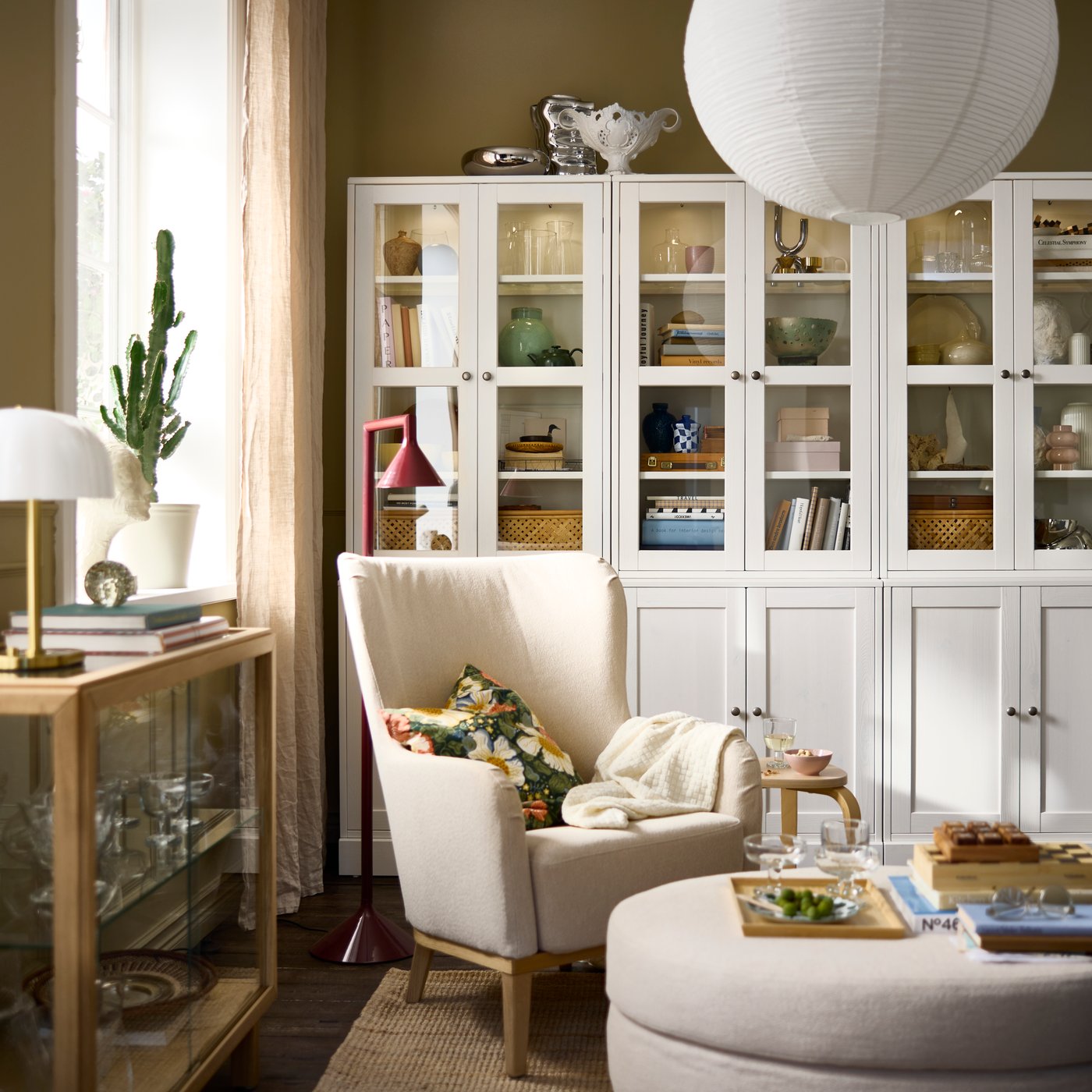 Salon aménagé avec un rangement HAVSTA blanc à portes vitrées, agrémenté d'objets décoratifs et de plantes.
