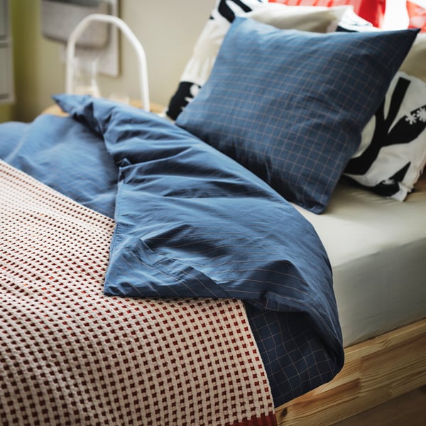 Dark blue/light brown DOFTAKLEJA bed linen on a GLAMBERGET extendable bed with a PELARTUJA bedspread on top.