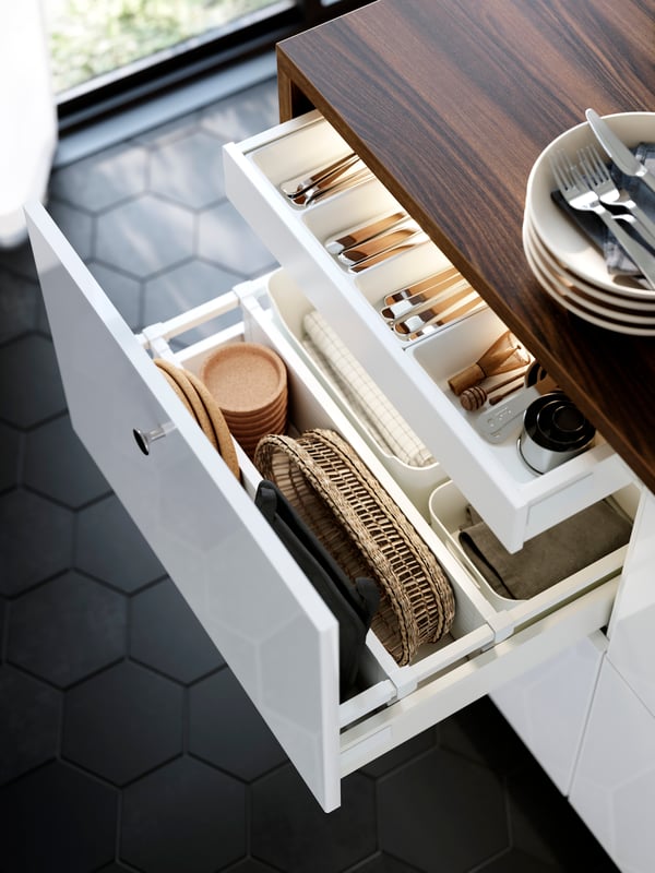 A large drawer in a cabinet with white RINGHULT kitchen fronts is pulled out and there are kitchen items organised inside.