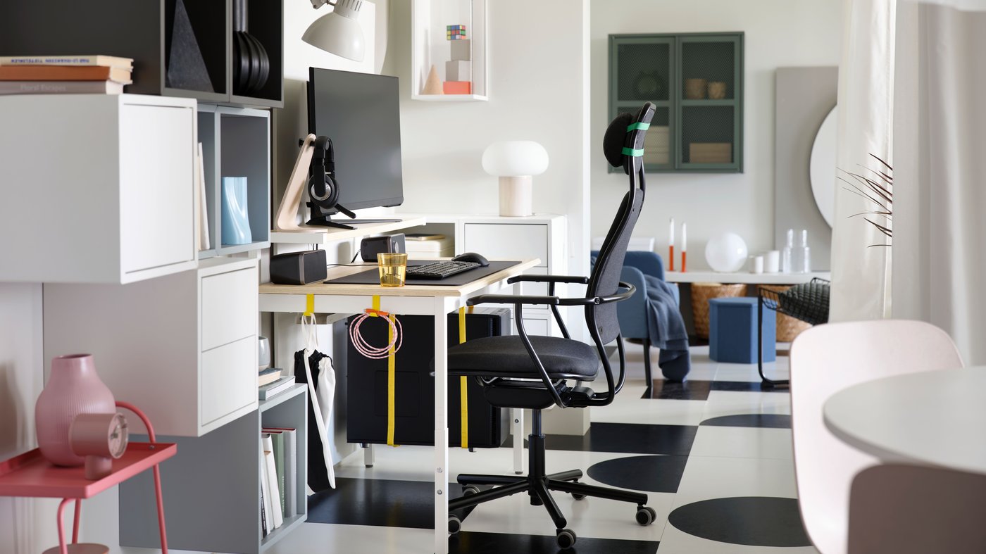 Poste de gaming avec bureau gamer UTVISNING motif frêne/blanc avec tablette et fauteuil gris foncé, dans un couloir blanc.