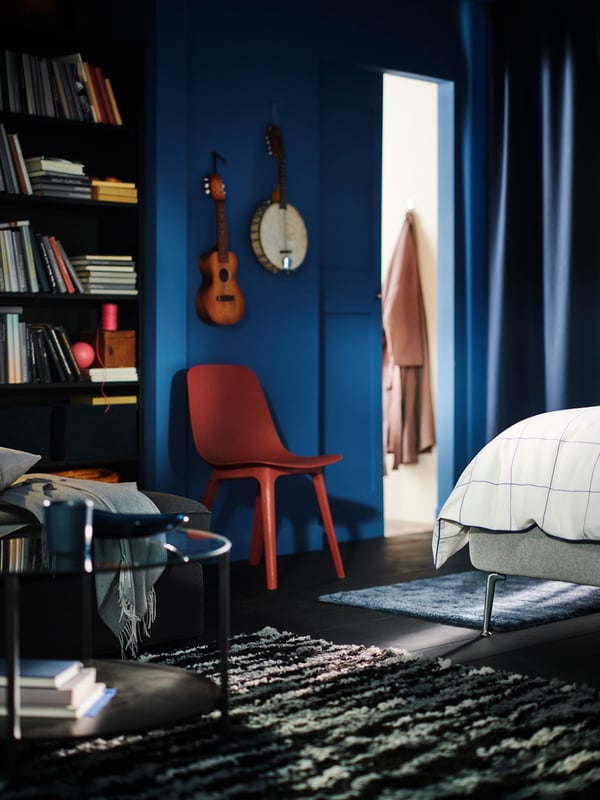 A black/grey/white BULLURREMSA high pile rug in a blue bedroom near a TUFJORD upholstered bed with a STOENSE rug beside it.