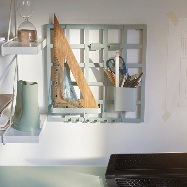 A SNICKRA storage board holds pens, pencils and a ruler. Other desk items sit on a pair of BERGSHULT/PERSHULT shelves.