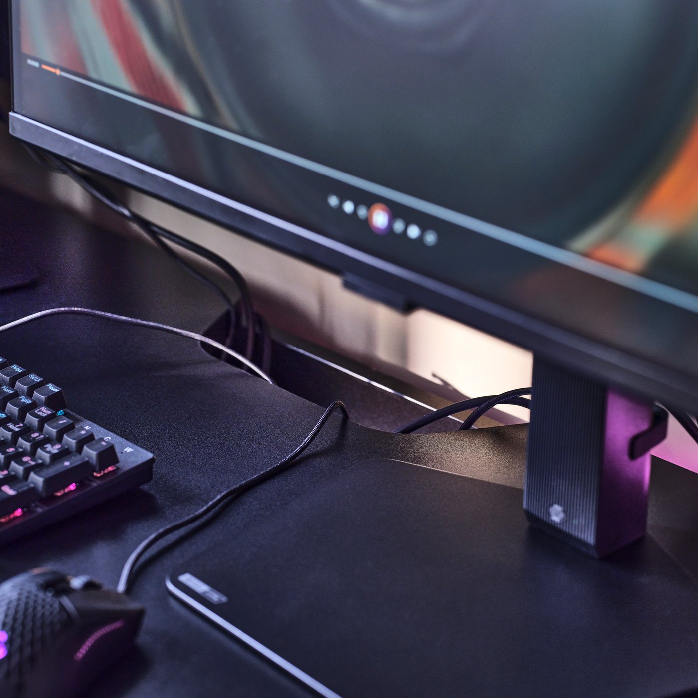Parts of a gaming setup on a FRÖSKELÅS gaming desk, where monitor, mouse, keyboard cords disappear into a desktop cutaway.