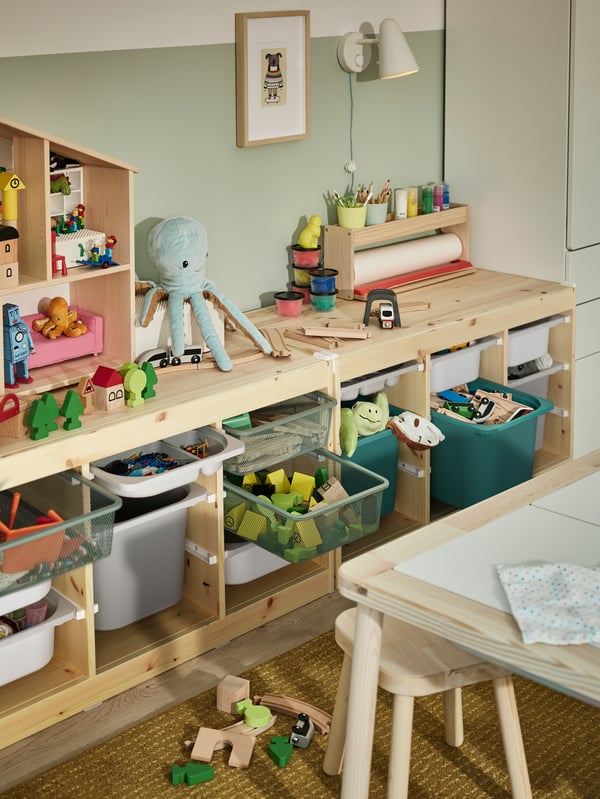 Mueble TROFAST de estructura de madera con cajones de plástico de colores gris, blanco y celeste.