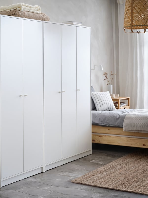 Two white KLEPPSTAD wardrobes – one 2-door and one 3-door side by side next to a pine UTÅKER stackable bed in a white room.