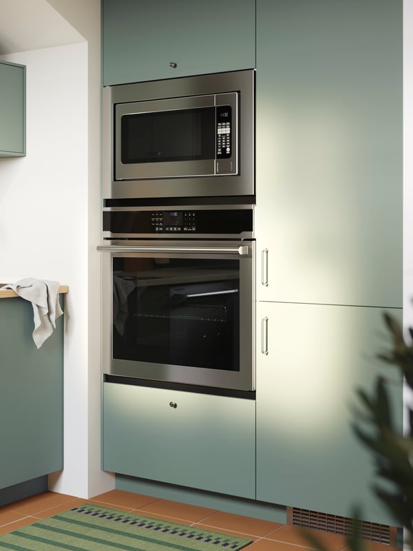 Cuisine équipée d’armoires avec des façades NICKEBO en gris vert, d’un ensemble réfrigérateur/congélateur intégré, d’un four encastrable et d’un four à micro-ondes.