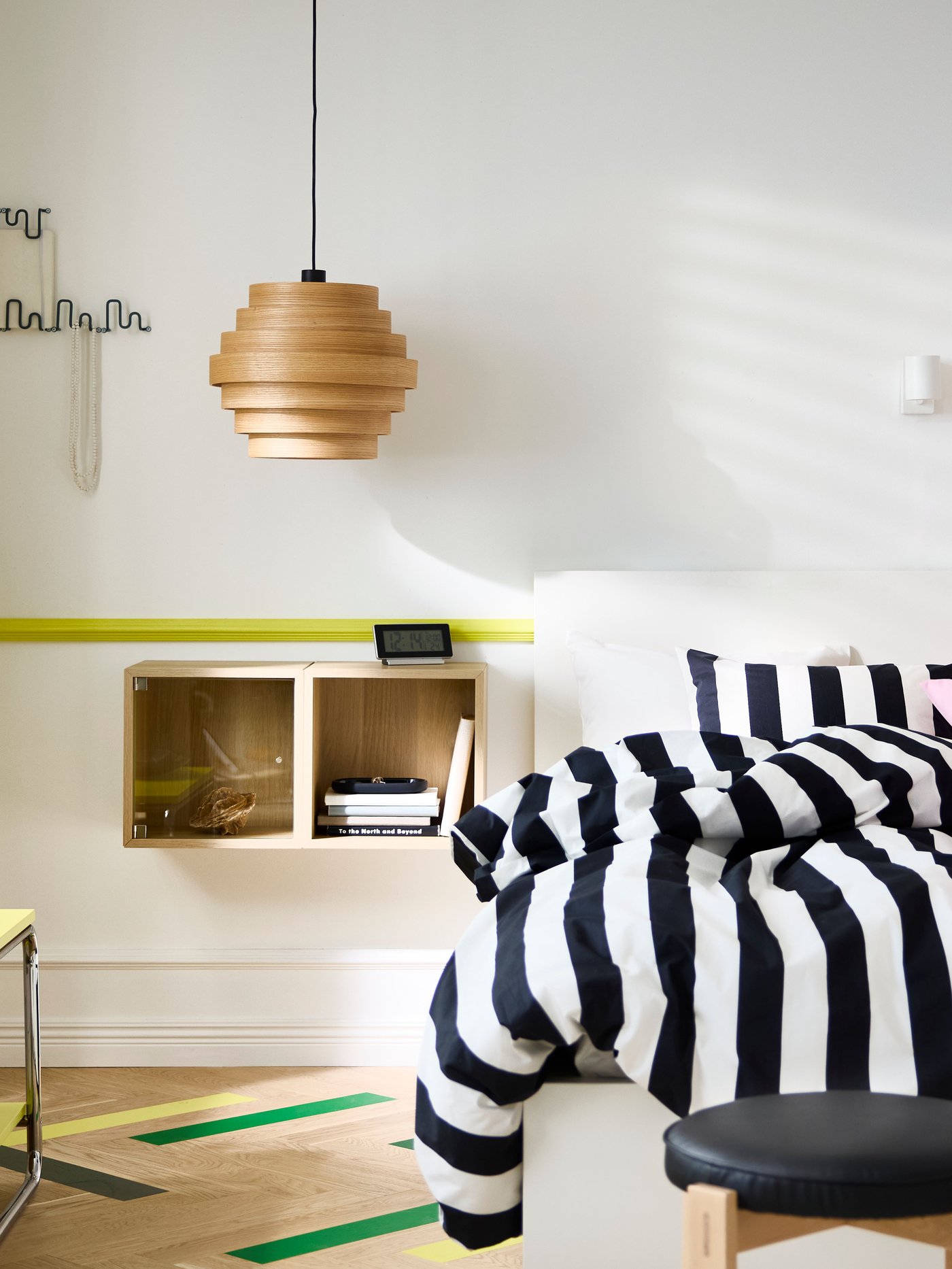 Bedroom with white walls and a double bed with black/white striped bedding to the left and bright pink to the right.