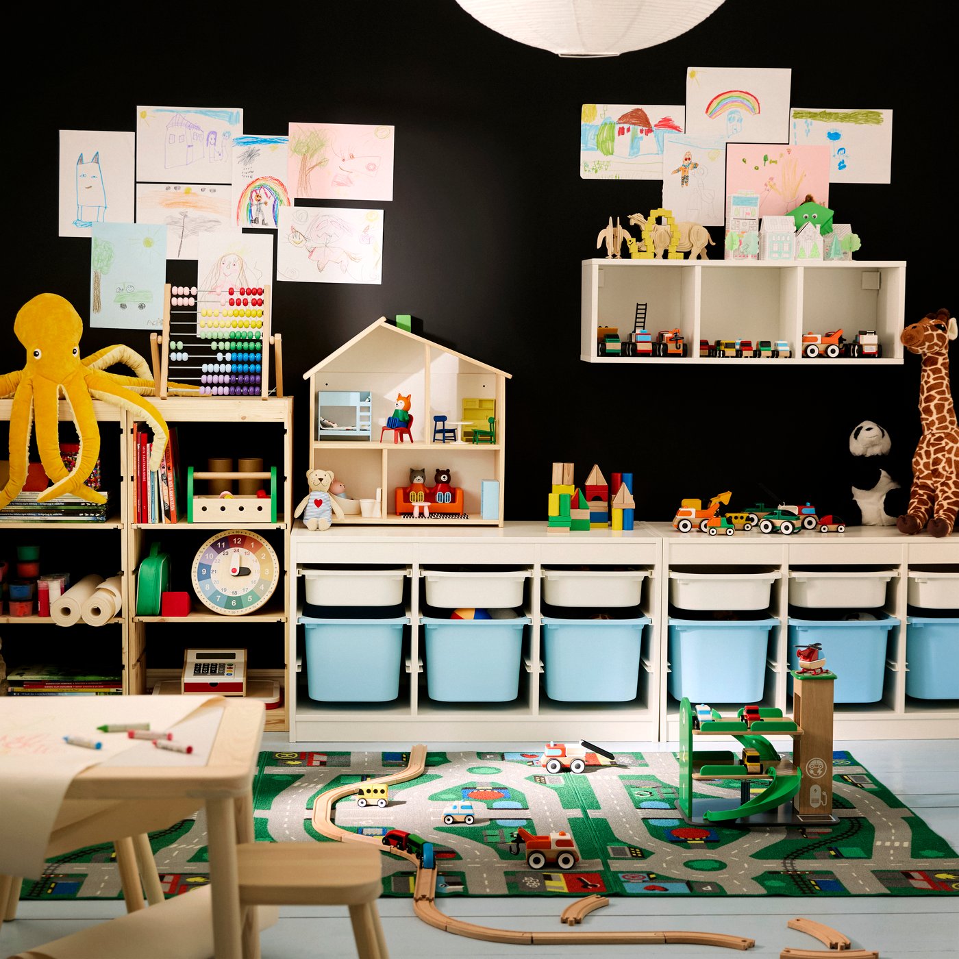 A children’s room with a black wall in the back, TROFAST storage system along that wall and LILLABO rug on floor.