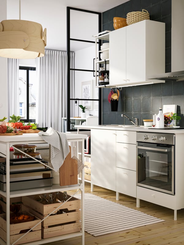 An ENHET kitchen in white with a mixture of open and closed storage and a kitchen island with boxes and other kitchen items.