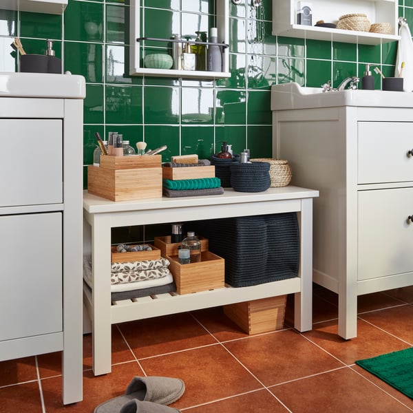 Una banqueta blanca HEMNES entre dos muebles de baño.