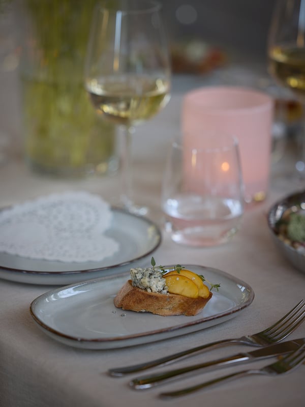 Un plato rectángular de bordes redondeados blanco con borde dorado GLADELIG con una comida gourmet. 