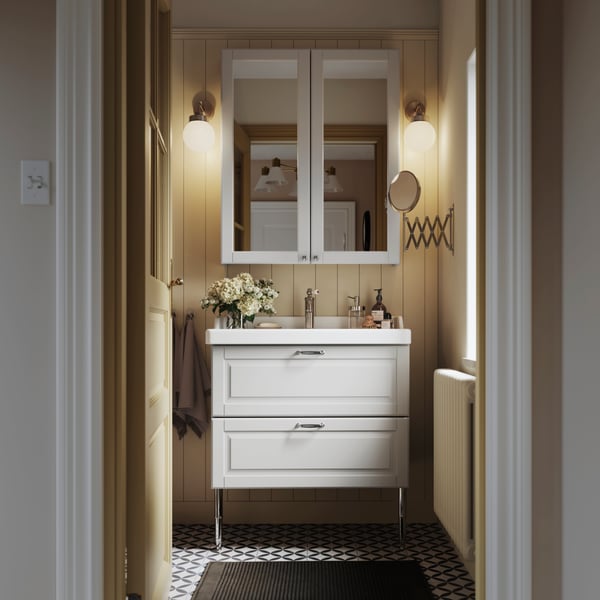 Baño con mueble para lavamanos de dos cajones y un botiquín.