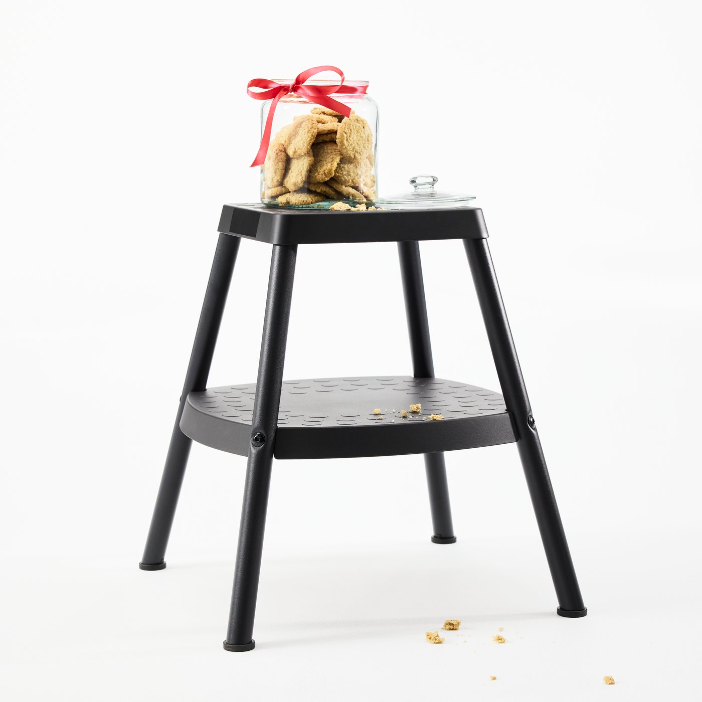 Marchepied HADDARP noir-gris où un bocal en verre ouvert rempli de biscuits est posé. Miettes sur le sol.