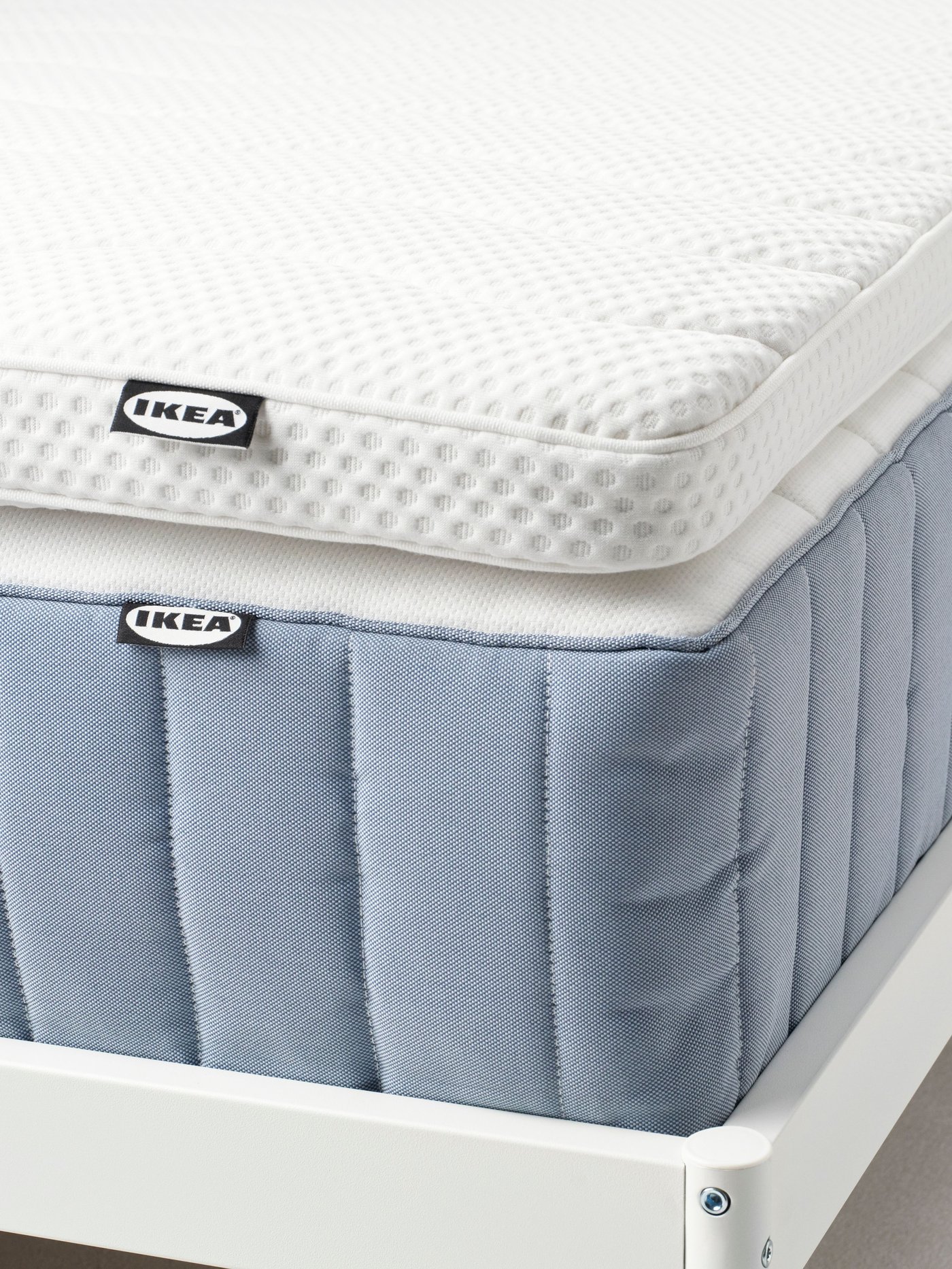 A white NORRSELE mattress topper lies on a bed in a bright bedroom.
