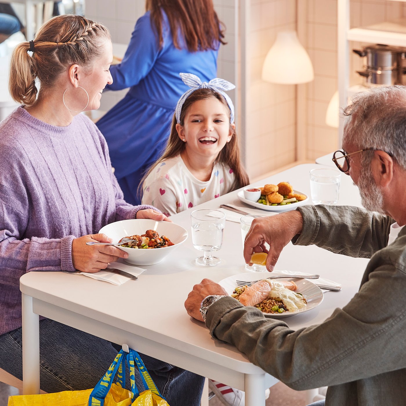 Gezin aan het eten in het IKEA restaurant met een jong meisje aan het lachen