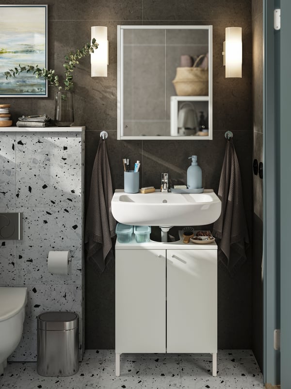 A bathroom with dark tiles featuring a NYSJÖN wash-basin cabinet and a NYSJÖN mirror with shelf.