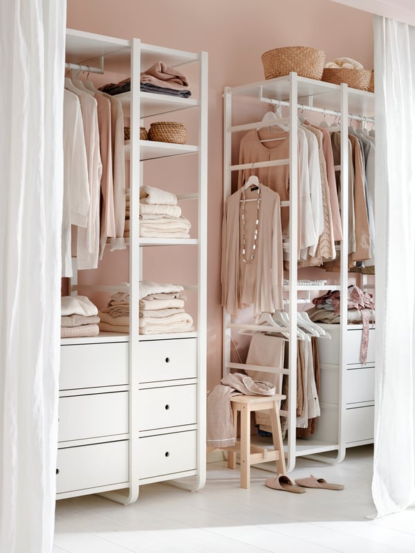Living-room where one wall is fitted with open, floor-length curtains, revealing a wall-wide wardrobe arrangement.