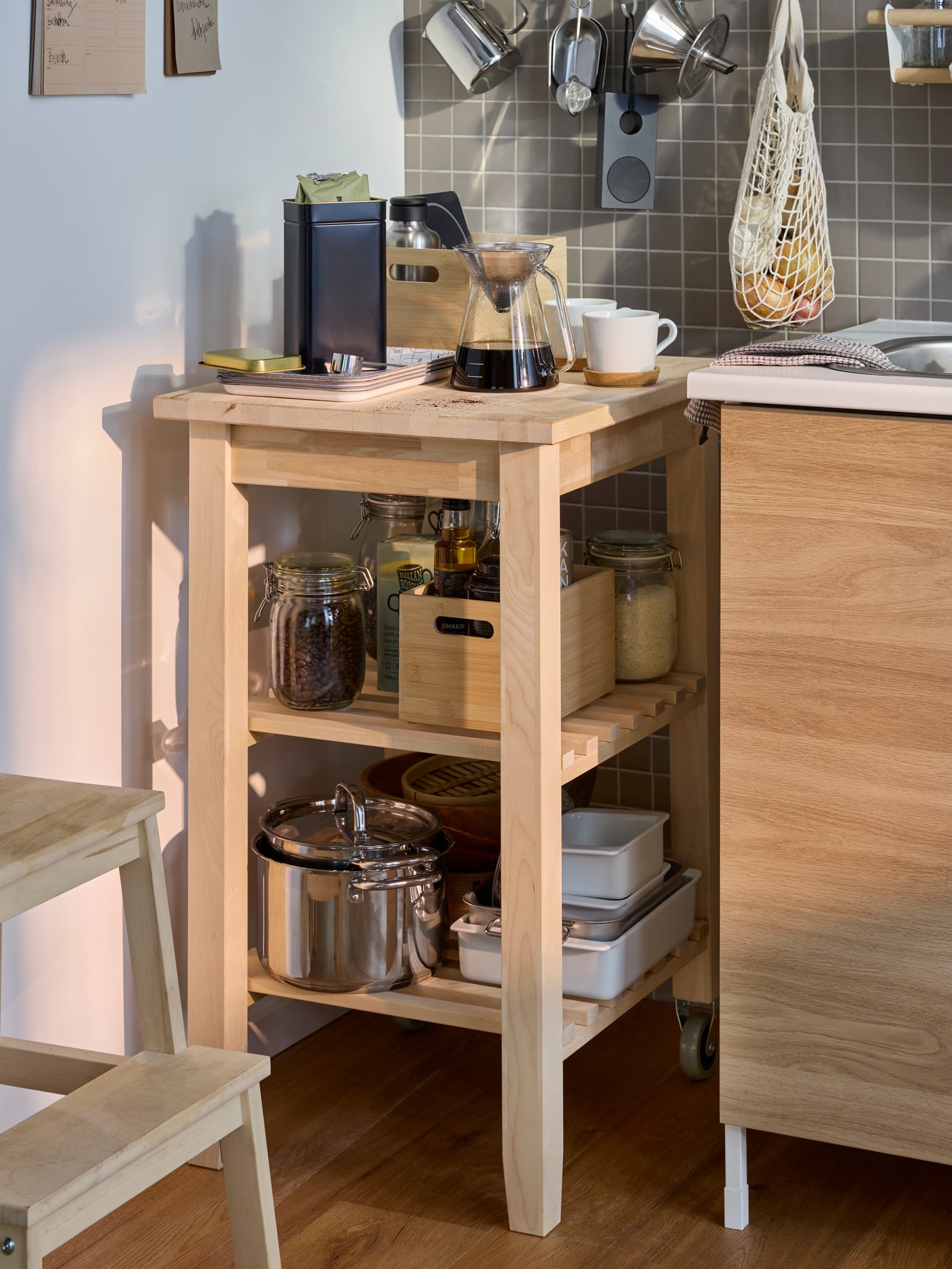 Auf einem BEKVÄM Servierwagen wurde unter anderem eine kleine Kaffeeecke angerichtet. Er steht am Ende einer Küche.